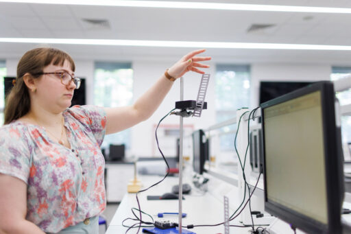 Undergraduate student demonstrating the "g-ladder" experiment, where a 3D-printed ladder is dropped through a light gate to determine its acceleration.